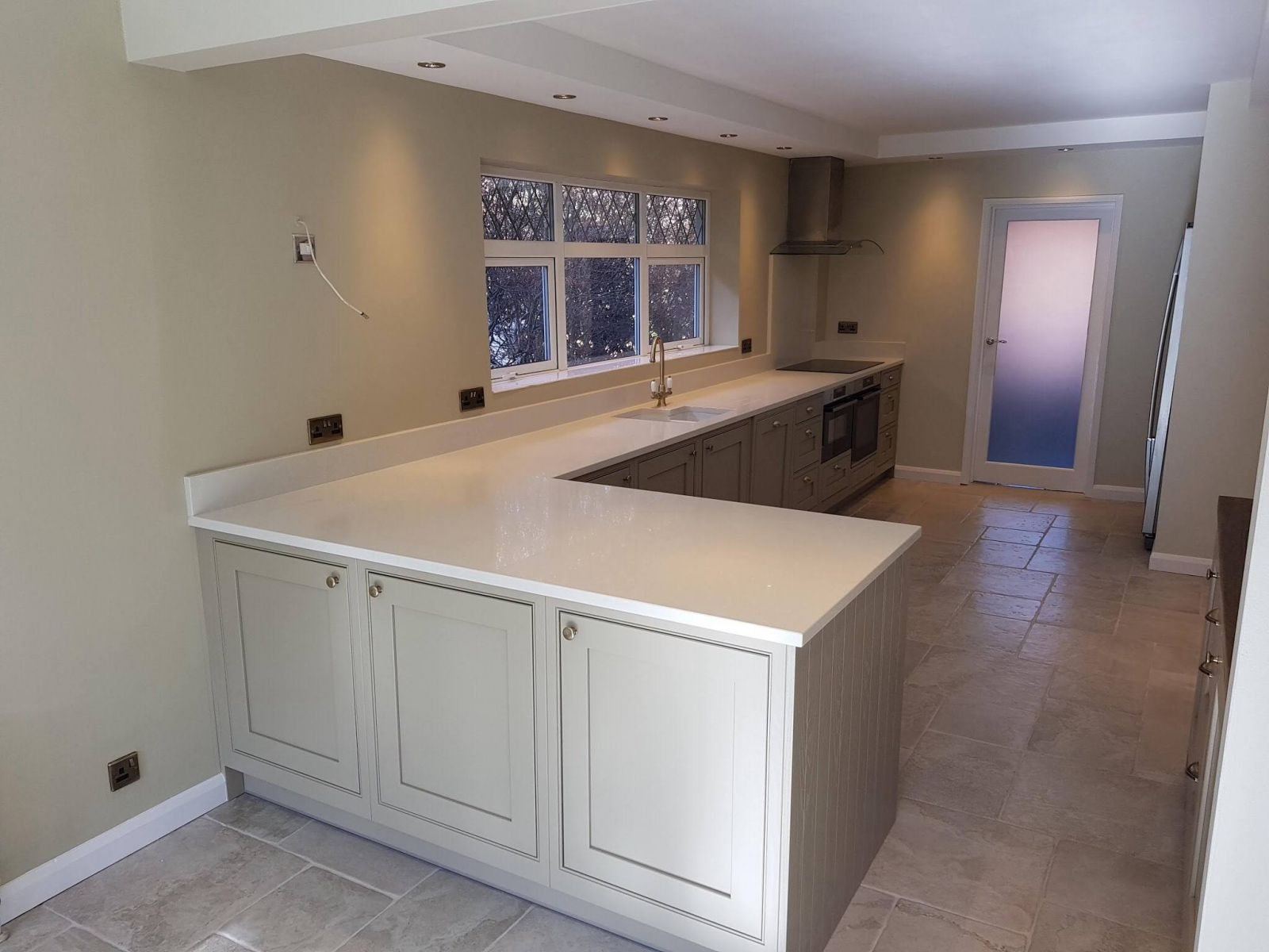 Pale grey in-frame Shaker kitchen with white worktop and peninsula